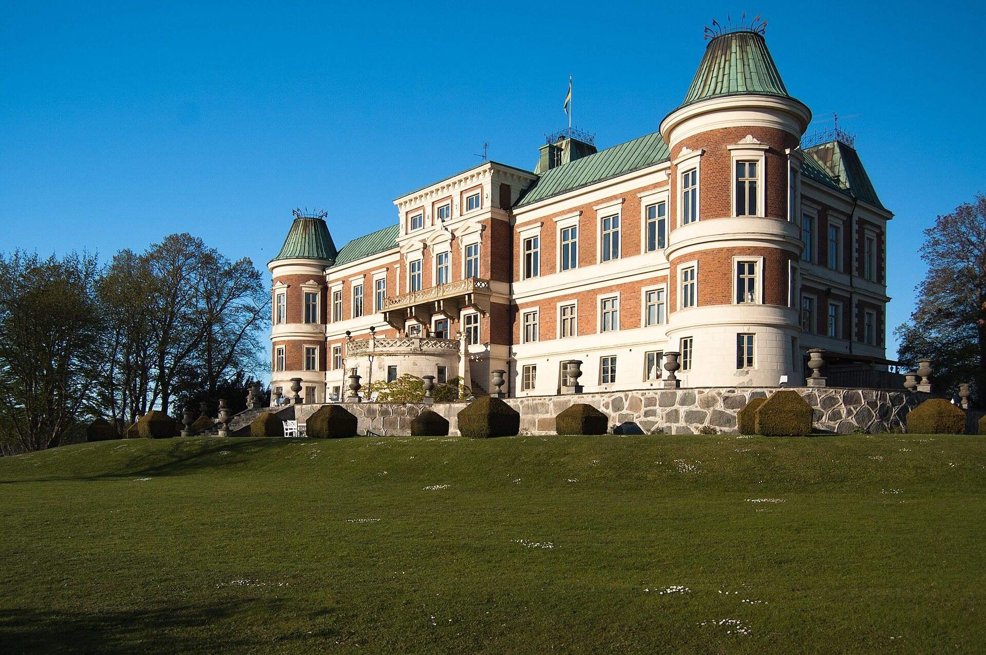 Häckeberga slott ved Genarp med grønne kobbertage og runde hjørnetårne, der rejser sig over græsplænen