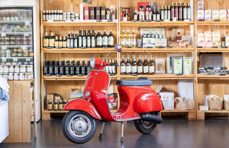 Hylder med italienske dagligvarer og en rød Vespa i en Italianissimo-butik