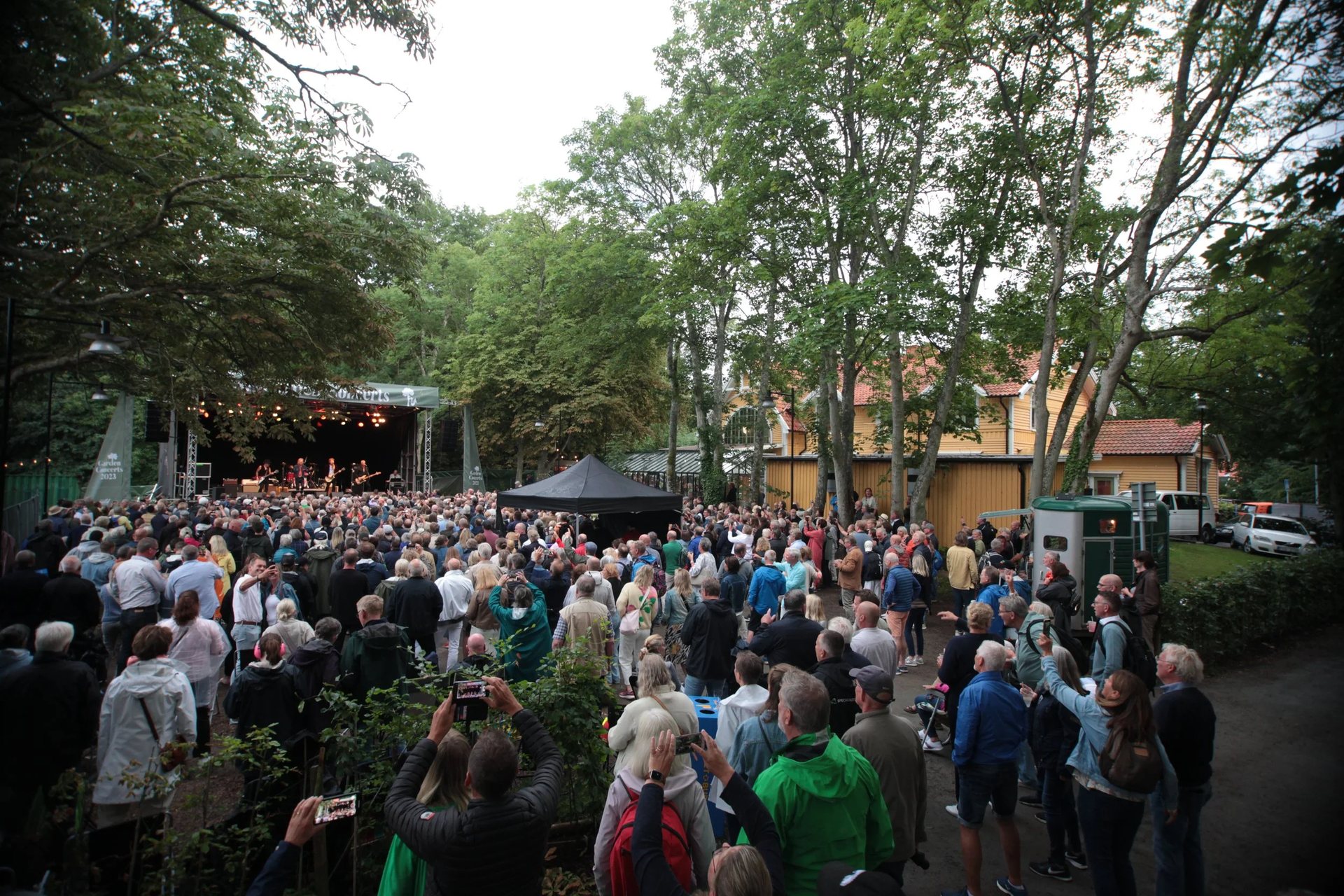 Publikum til Garden Concerts under træerne foran scenen på Bjerreds Station